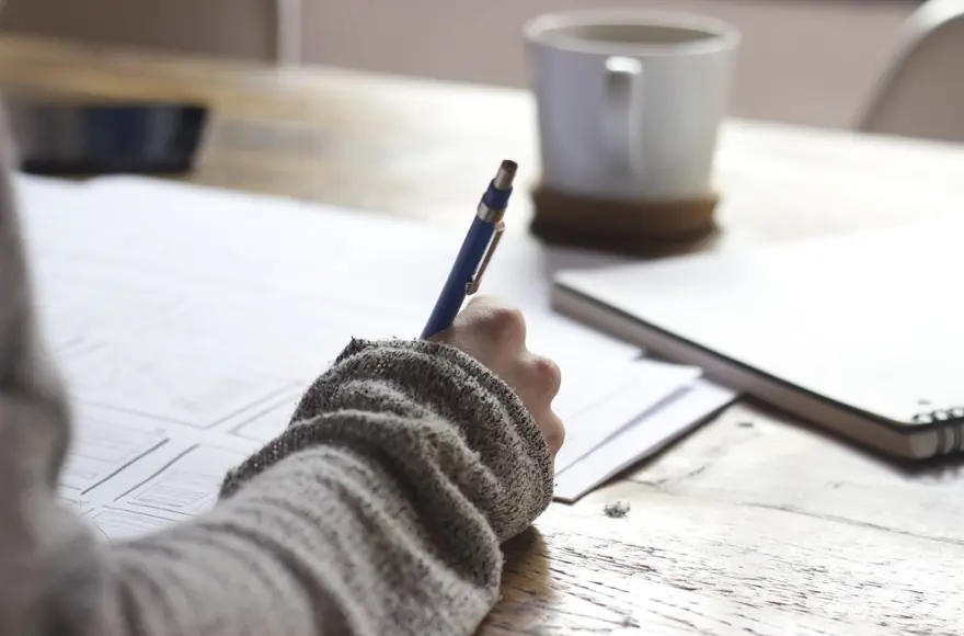 A student writing notes at a desk.