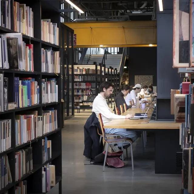 Students studying at tables in a modern library.